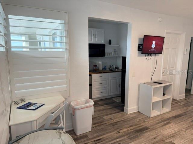 A bedroom features a bed, white walls, wood-look flooring, and a small dining area — 935 S ATLANTIC AVE UNIT 255, DAYTONA BEACH, FL