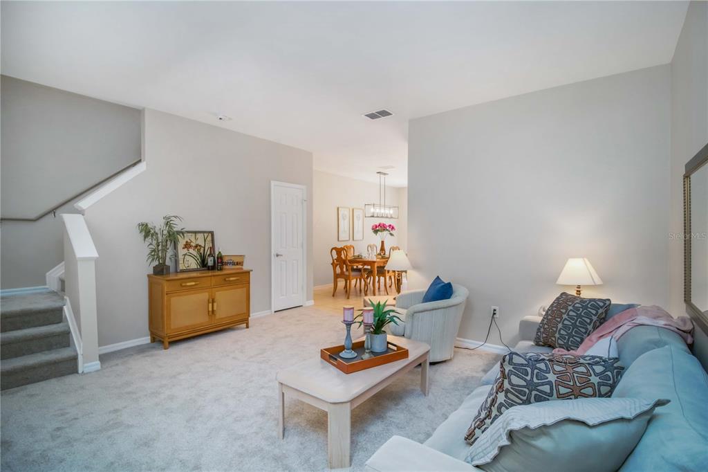 A living room with light carpet, a tan cabinet, and a dining area beyond — 7794 PLANTATION CIRCLE, BRADENTON, FL