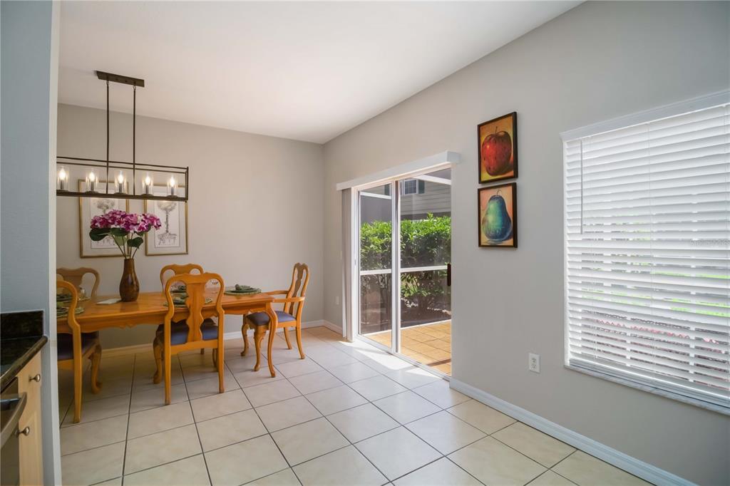 A dining area with tile floors, a wooden table, and a sliding glass door to a patio — 7794 PLANTATION CIRCLE, BRADENTON, FL
