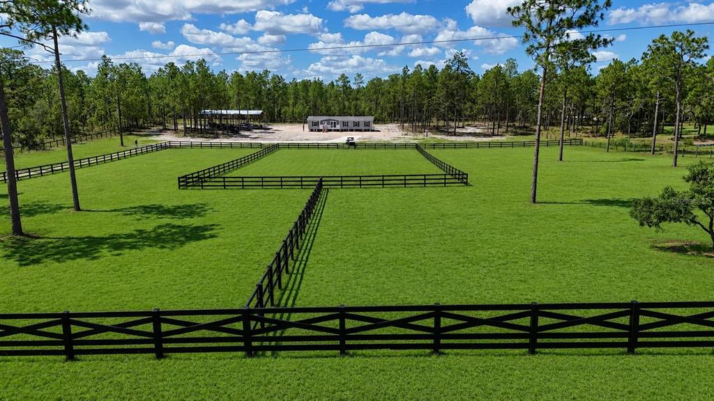 An aerial view shows a large, fenced grassy pasture with a building in the background — 14270 SE 60 STREET, MORRISTON, FL