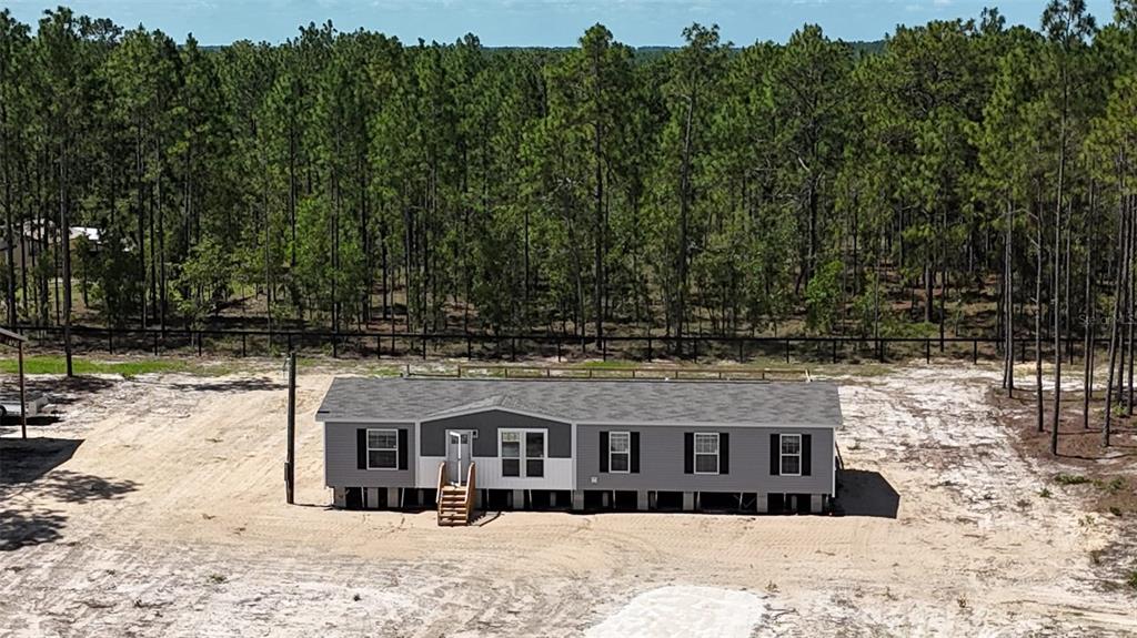 An aerial view of a single-story manufactured home situated on a cleared, sandy lot — 14270 SE 60 STREET, MORRISTON, FL