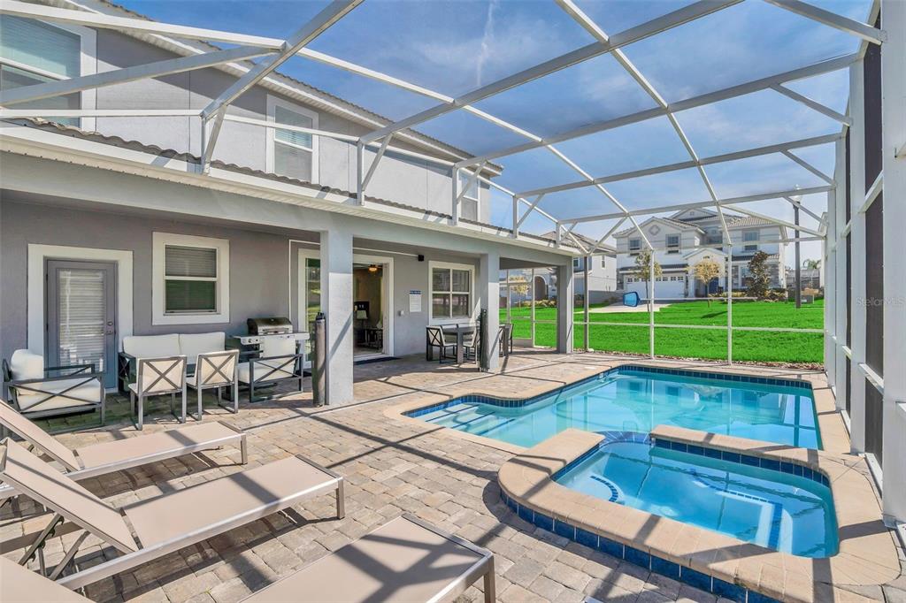 A screened-in patio features a swimming pool, a hot tub, and outdoor lounge furniture — 1598 SANDBAGGER, DAVENPORT, FL
