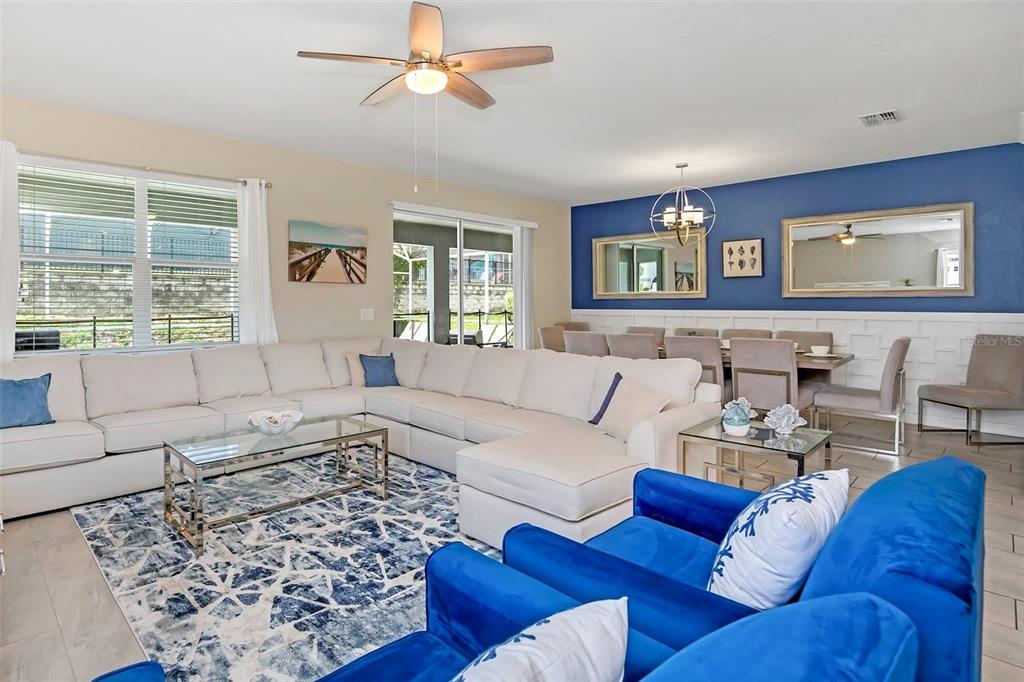 A living room features a large sectional sofa, blue armchairs, and a dining area nearby — 1598 SANDBAGGER, DAVENPORT, FL