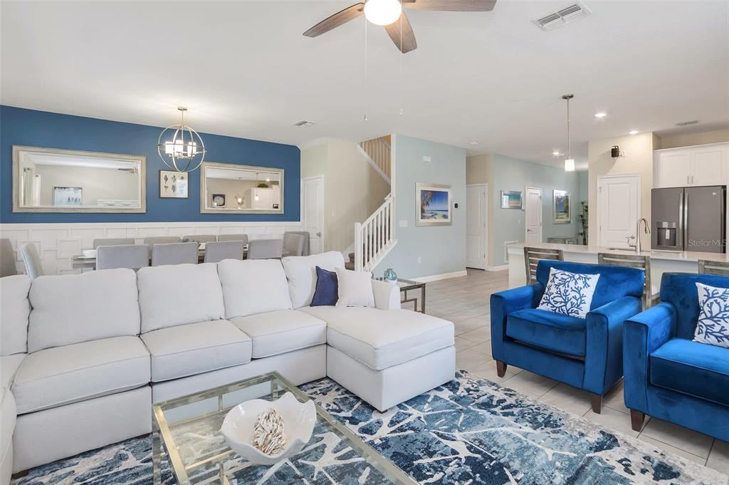 An open-concept living and dining area features a white sectional, blue armchairs, and blue walls — 1598 SANDBAGGER, DAVENPORT, FL