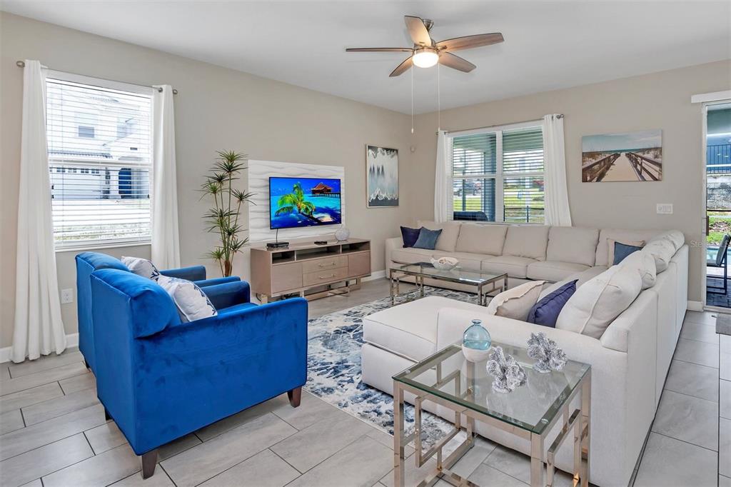 A living room features a blue armchair, a large sectional sofa, and a television console — 1598 SANDBAGGER, DAVENPORT, FL