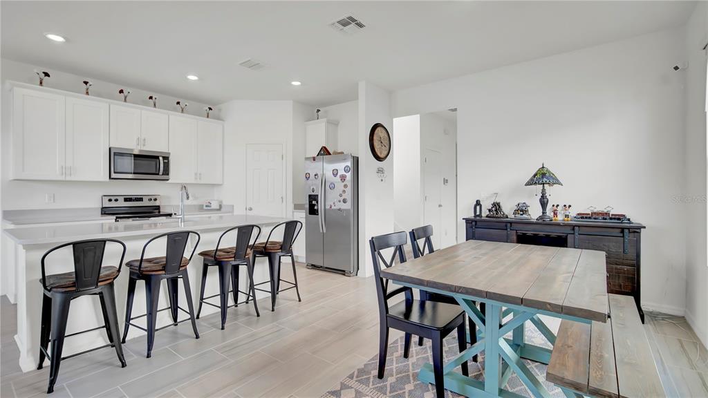 A kitchen with white cabinets and a dining area featuring a wooden table and chairs — 4704 HOMESTEAD TRAIL, ST CLOUD, FL