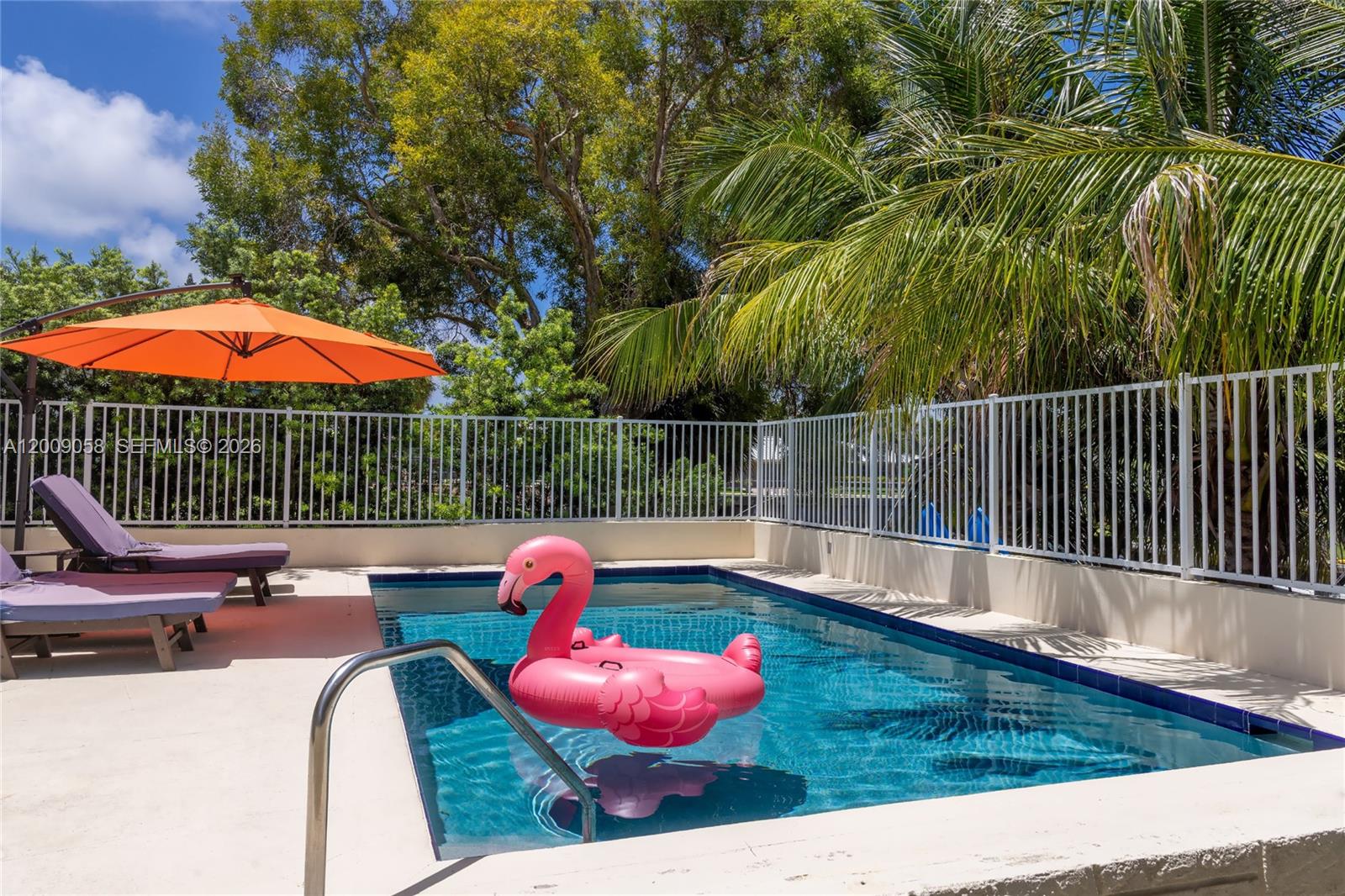 A swimming pool with a pink flamingo float sits on a patio with lounge chairs — 155 SE 19th Ave # 0, Deerfield Beach FL 33441, DEERFIELD BEACH, FL