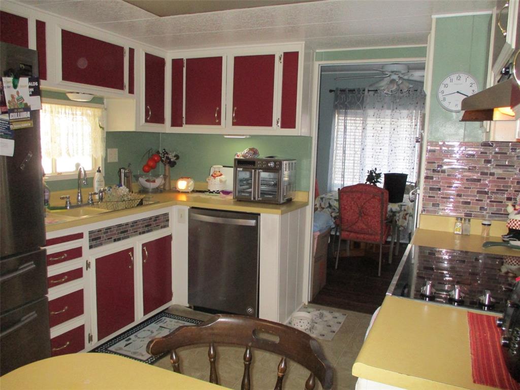 A kitchen features red and white cabinets, yellow countertops, and a tiled backsplash — 38536 CONE DRIVE, ZEPHYRHILLS, FL