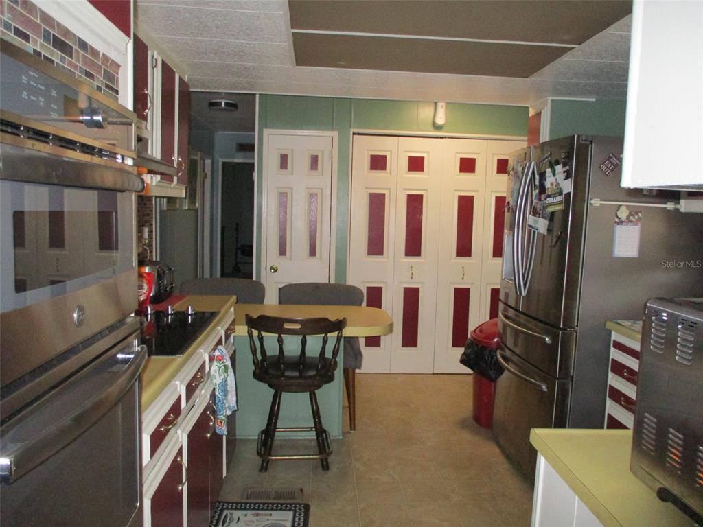 A kitchen features a wall oven, stainless steel refrigerator, and a small breakfast bar area — 38536 CONE DRIVE, ZEPHYRHILLS, FL