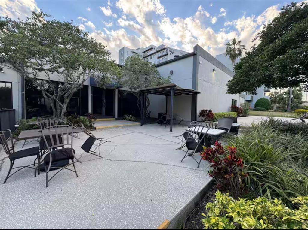 An outdoor patio area features metal tables and chairs set against a modern building exterior — 6165 CARRIER DRIVE UNIT 3104, ORLANDO, FL