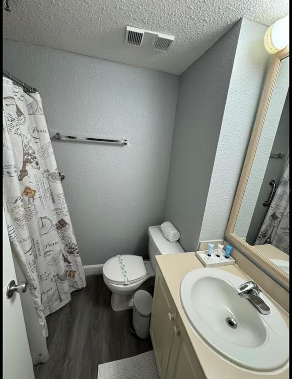 A bathroom features a vanity with a sink, a toilet, and a shower with a curtain — 6165 CARRIER DRIVE UNIT 3104, ORLANDO, FL
