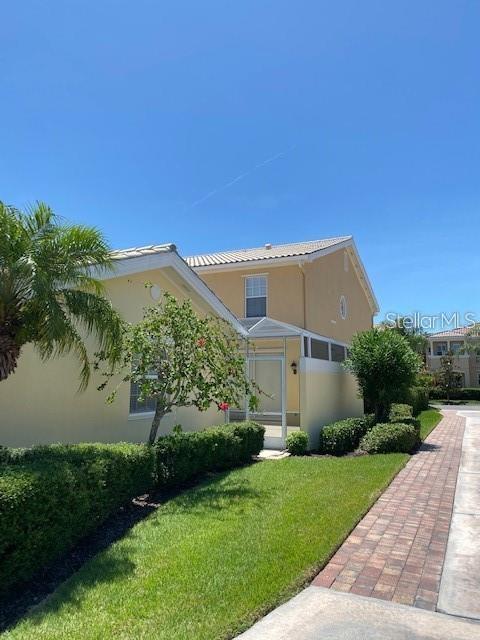 A two-story yellow house features a screened-in porch and a brick walkway — 5361 ELISEO STREET, SARASOTA, FL