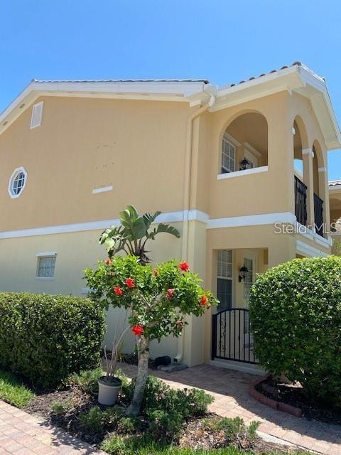 A two-story tan stucco building features a covered balcony and a small flowering tree — 5361 ELISEO STREET, SARASOTA, FL