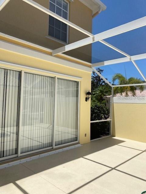A covered patio with a concrete floor and sliding glass doors leads to a screened enclosure — 5361 ELISEO STREET, SARASOTA, FL