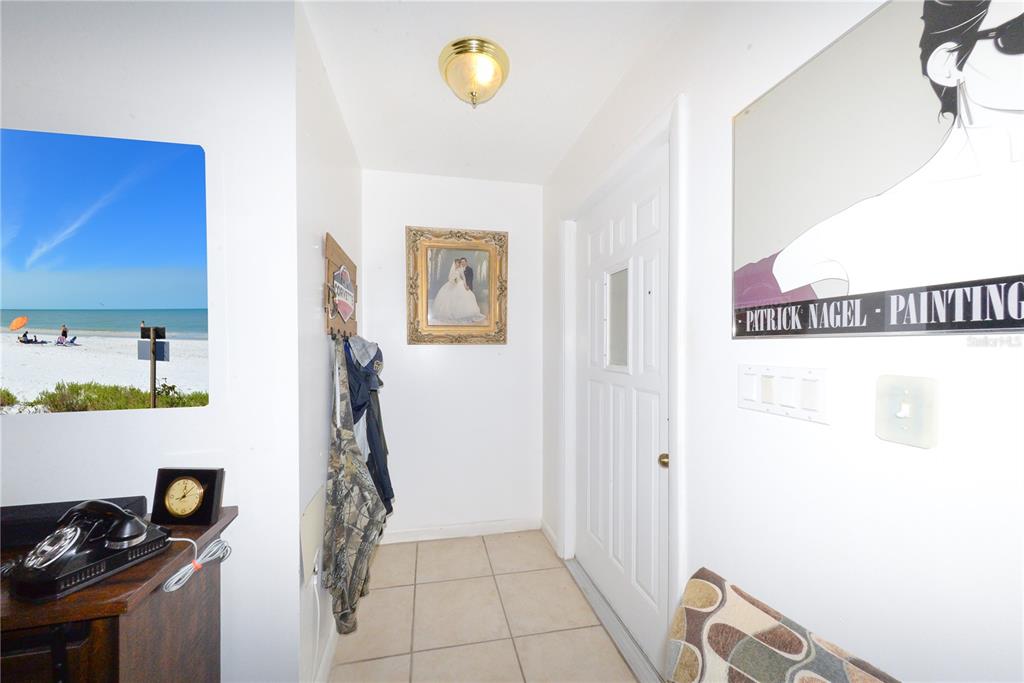 An entryway with tile flooring, a white door, wall art, and a vintage telephone — 451 READING STREET NW, PORT CHARLOTTE, FL