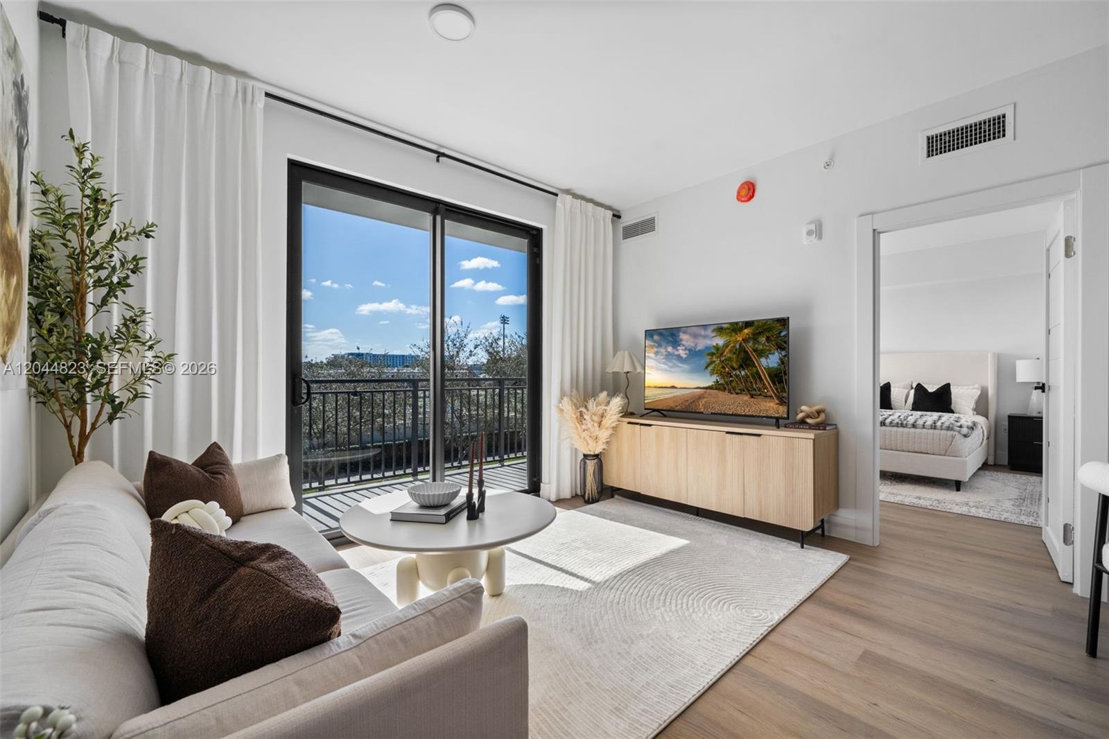 A living room features a beige sofa, a round coffee table, and a media console — 2479 NE 192nd St # 207, Miami FL 33180, MIAMI, FL