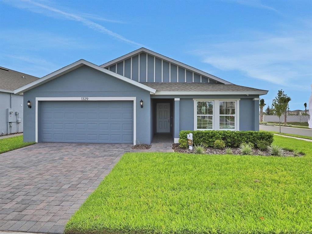 A blue single-story house with a two-car garage and a paved driveway — 123 BOTTLE BRUSH DRIVE, HAINES CITY, FL