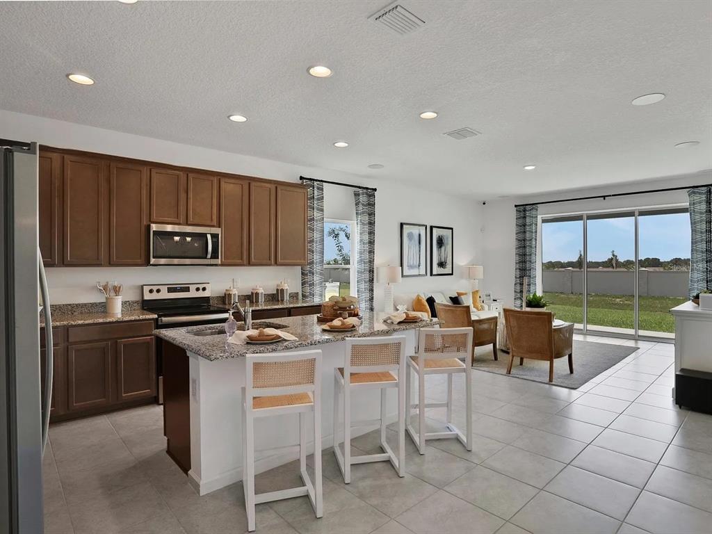 A living room features a white media console, a round wooden coffee table, and chairs — 123 BOTTLE BRUSH DRIVE, HAINES CITY, FL