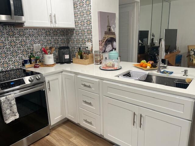 A kitchen features white cabinets, stainless steel appliances, and a patterned tile backsplash — 31 Capri A # 31, Delray Beach FL 33484, DELRAY BEACH, FL