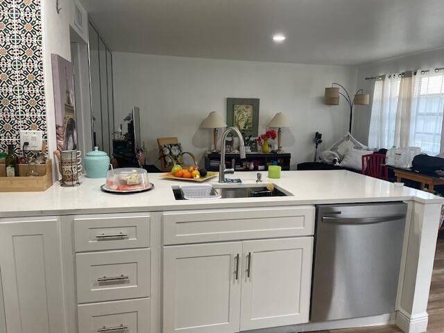 A kitchen island with white cabinets and a stainless steel dishwasher faces a living area — 31 Capri A # 31, Delray Beach FL 33484, DELRAY BEACH, FL