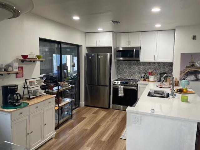 A modern kitchen features white cabinetry, stainless steel appliances, a kitchen island, and wood flooring — 31 Capri A # 31, Delray Beach FL 33484, DELRAY BEACH, FL