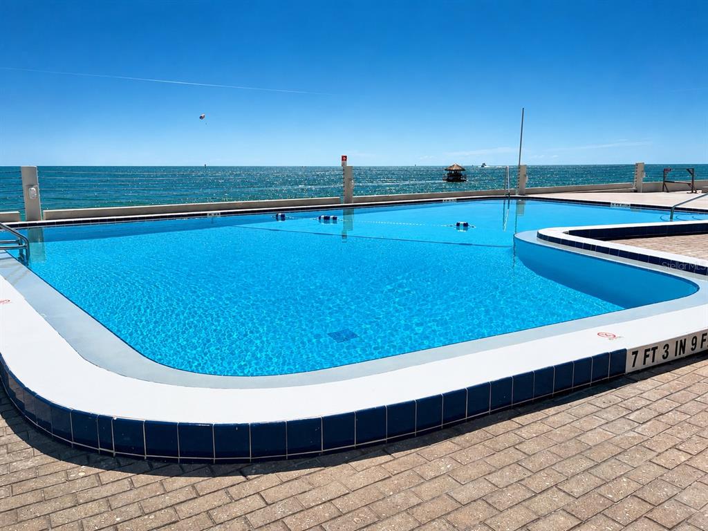 An outdoor swimming pool overlooks the ocean with a paved deck and safety railings — 450 S GULFVIEW BOULEVARD UNIT 708, CLEARWATER BEACH, FL