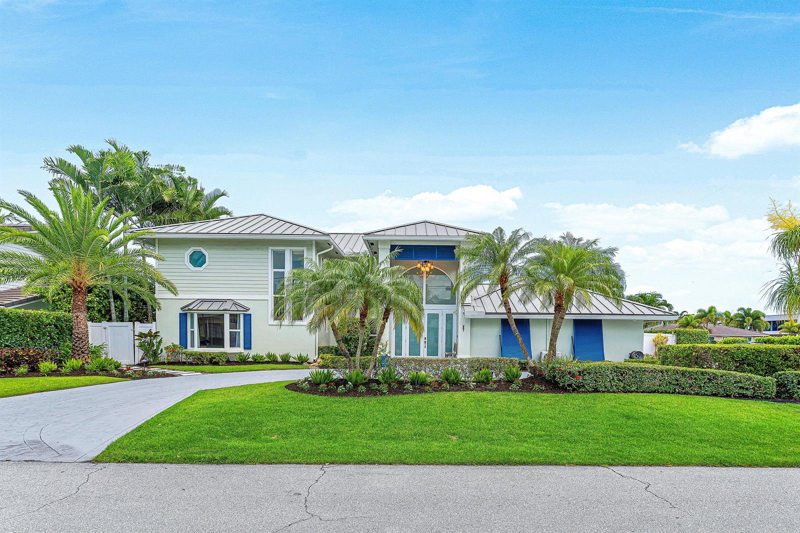 A two-story light green house with a metal roof, blue shutters, and palm trees — 6500 NE 7th Avenue, Boca Raton FL 33487, BOCA RATON, FL