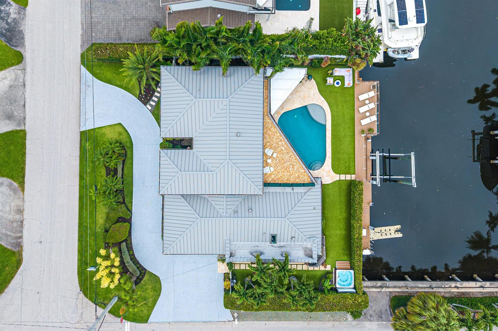 An aerial view shows a waterfront house with a metal roof, pool, and boat dock — 6500 NE 7th Avenue, Boca Raton FL 33487, BOCA RATON, FL
