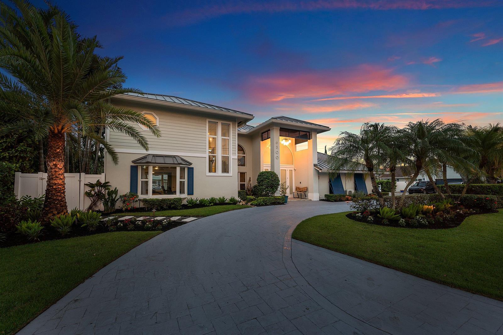 A two-story house with a paved driveway, palm trees, and a sunset sky — 6500 NE 7th Avenue, Boca Raton FL 33487, BOCA RATON, FL