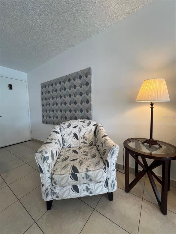 A patterned armchair sits next to a small glass-topped side table and lamp on tile flooring — 5349 ISLA VERDE AVENUE UNIT 402, CAROLINA, PR