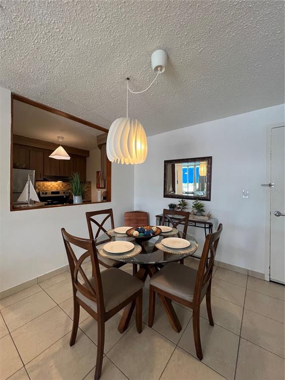 A dining area features a glass-topped table, four wooden chairs, and a modern pendant light — 5349 ISLA VERDE AVENUE UNIT 402, CAROLINA, PR