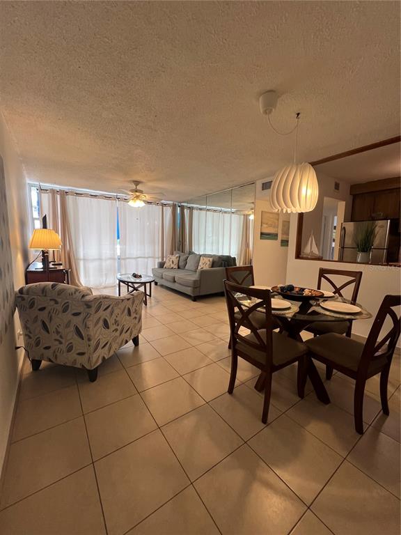 An open-concept living and dining area features tile flooring, a sofa, and a pendant light — 5349 ISLA VERDE AVENUE UNIT 402, CAROLINA, PR