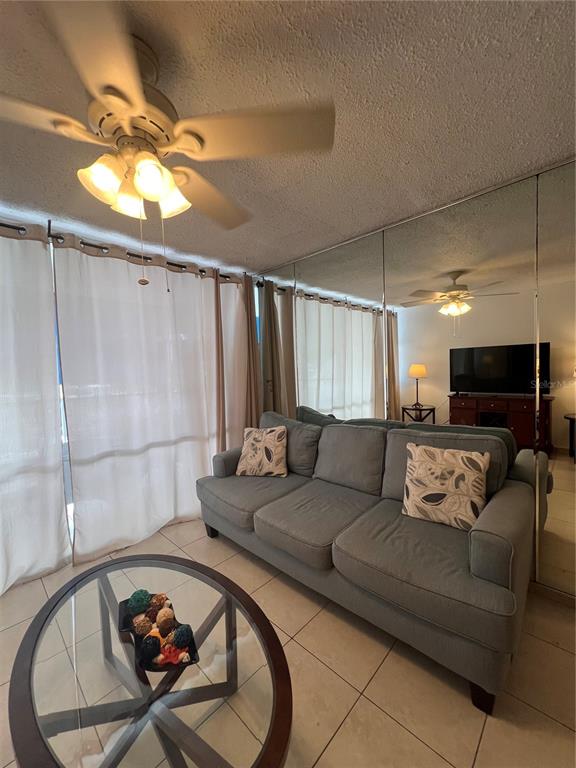 A living room features a gray sofa, a glass coffee table, and a mirrored wall — 5349 ISLA VERDE AVENUE UNIT 402, CAROLINA, PR