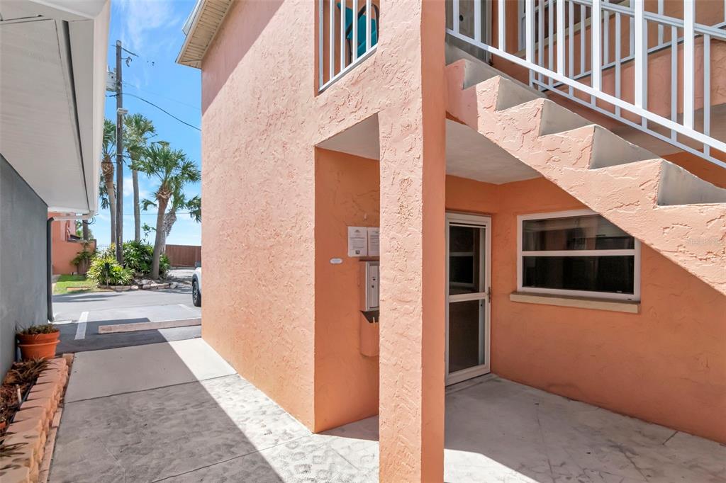 An exterior view of a peach-colored building with an outdoor staircase and a ground-level entrance — 3514 GULF BOULEVARD UNIT 3, ST PETE BEACH, FL