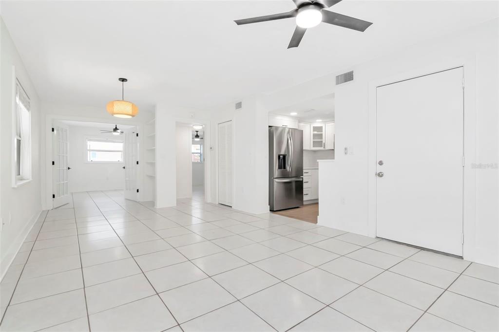 A bright, open-concept living area features white tile flooring, a ceiling fan, and a kitchen — 3514 GULF BOULEVARD UNIT 3, ST PETE BEACH, FL