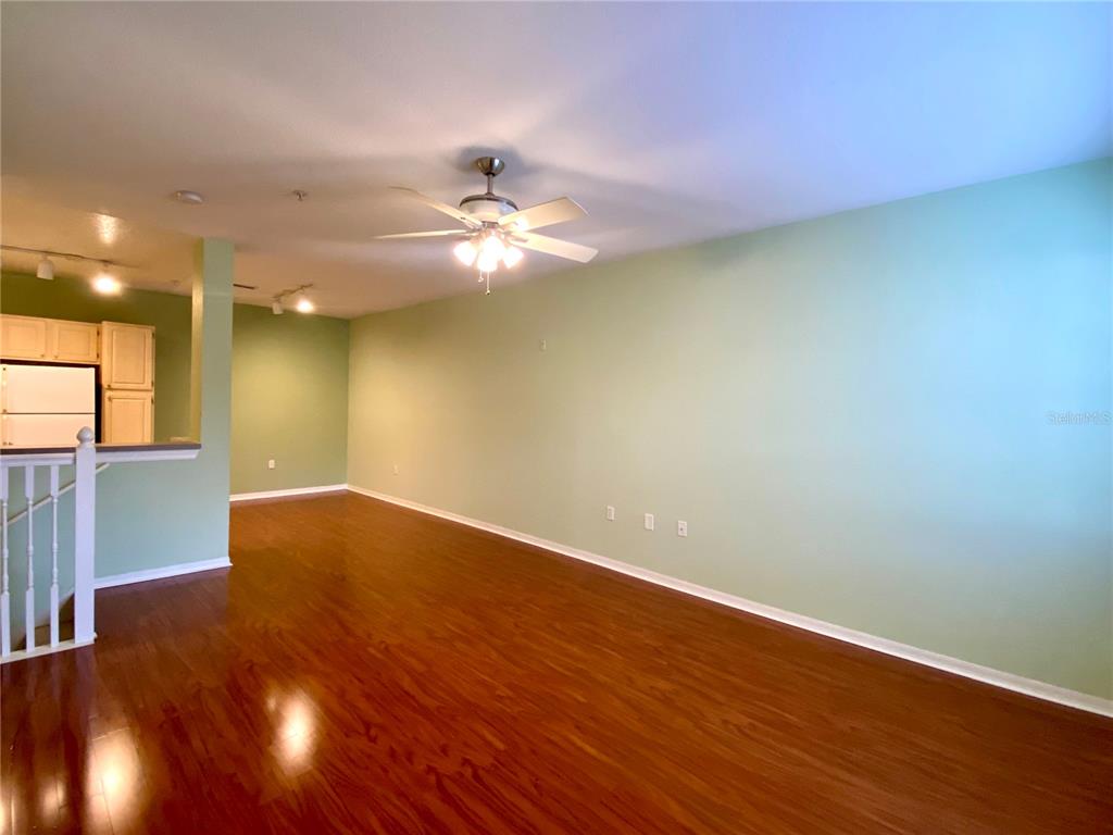 An empty living room features light green walls, a ceiling fan, and dark wood flooring — 1608 LEGACY PARK DRIVE UNIT 1608, MAITLAND, FL