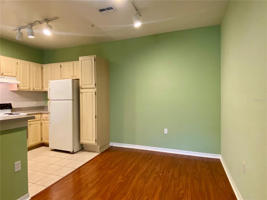 A kitchen with light-colored cabinets and a white refrigerator opens to a green-walled dining area — 1608 LEGACY PARK DRIVE UNIT 1608, MAITLAND, FL