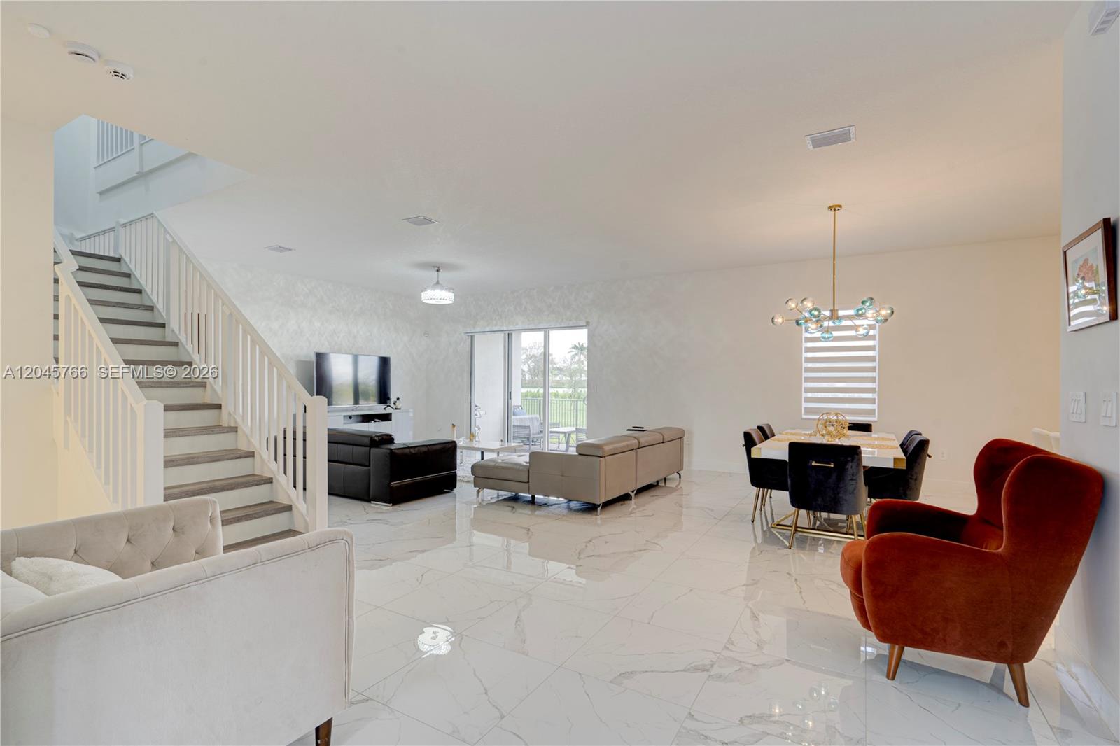 A bright, open-concept living and dining area features white marble floors and a staircase — 4367 SW 123 ln, Davie FL 33330, DAVIE, FL