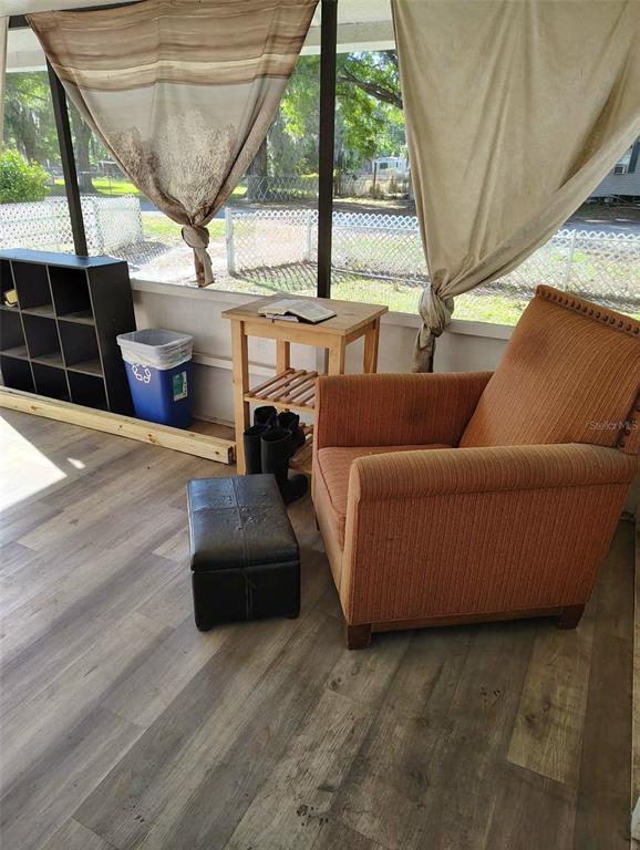 A sunroom features wood-look flooring, an orange armchair, a small side table, and a storage unit — 2974 BRENDA LANE, AUBURNDALE, FL