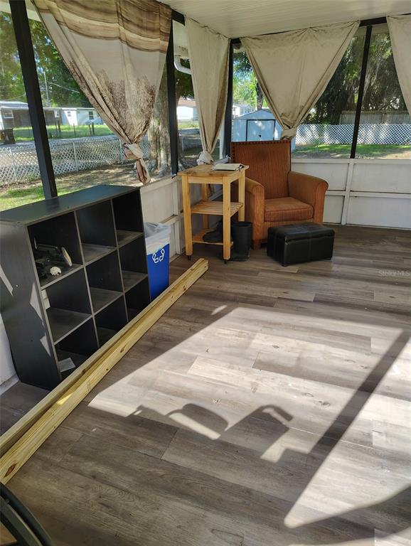 A screened-in porch with wood-look flooring, a storage cubby, and an armchair — 2974 BRENDA LANE, AUBURNDALE, FL