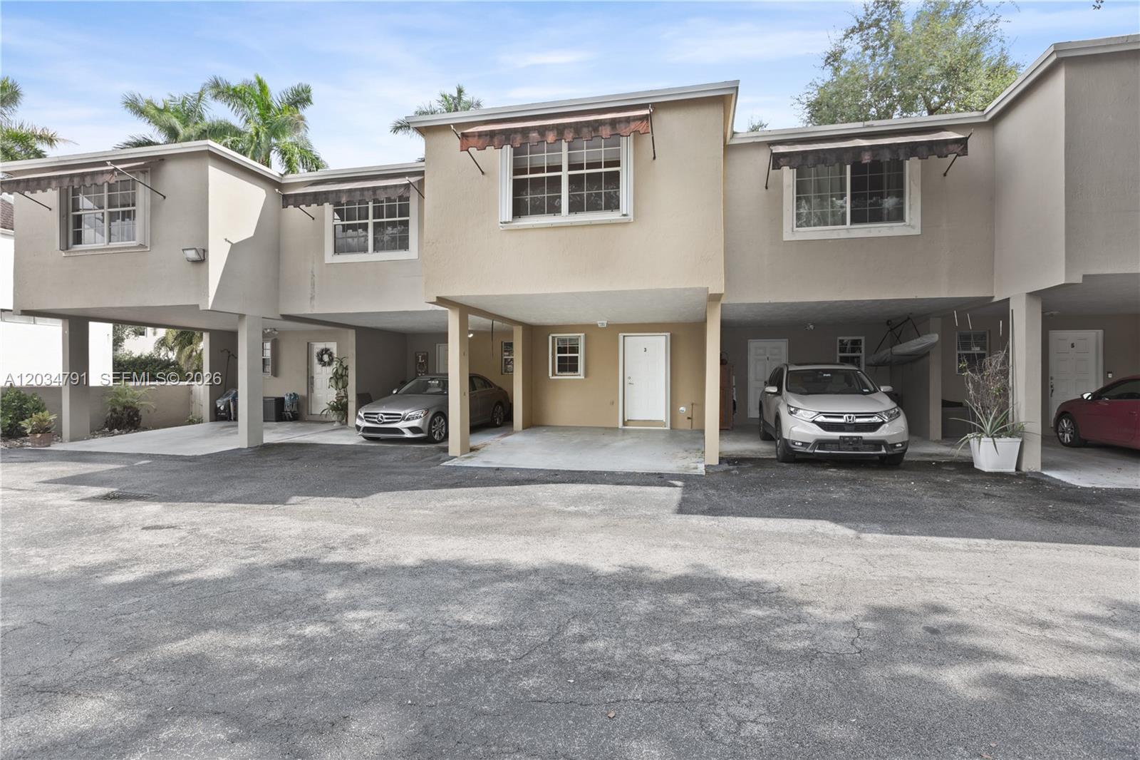 A row of multi-story townhouses features covered ground-level parking spaces and white entry doors — 3130 Bird Ave # 3, Miami FL 33133, MIAMI, FL