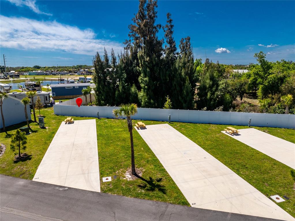 An outdoor view shows three paved RV pads with picnic tables and a white fence — 443 HORIZON ROAD, PUNTA GORDA, FL