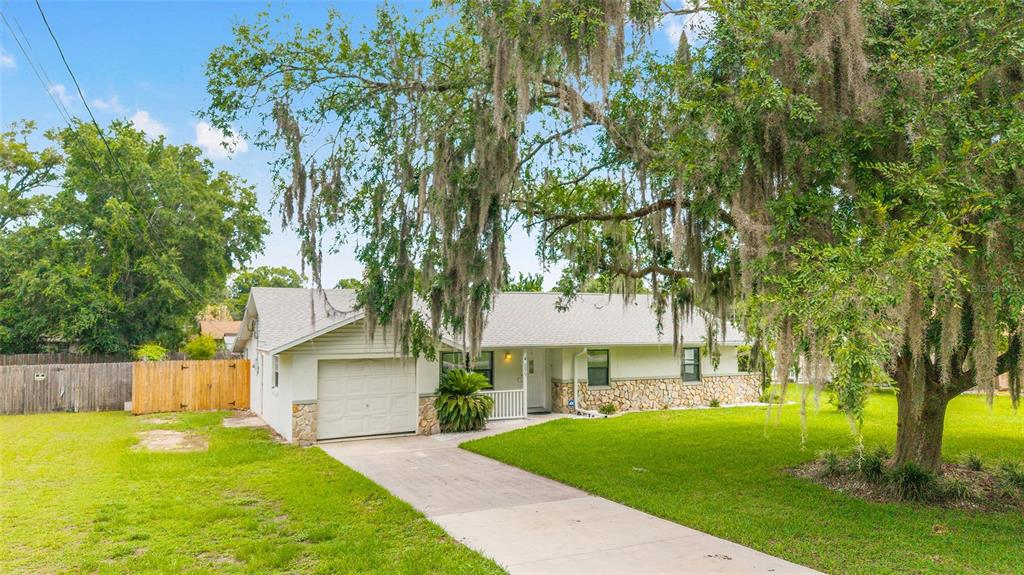 A single-story house with a stone facade, a white garage, and a large tree with moss — 2079 NE 43RD STREET, OCALA, FL