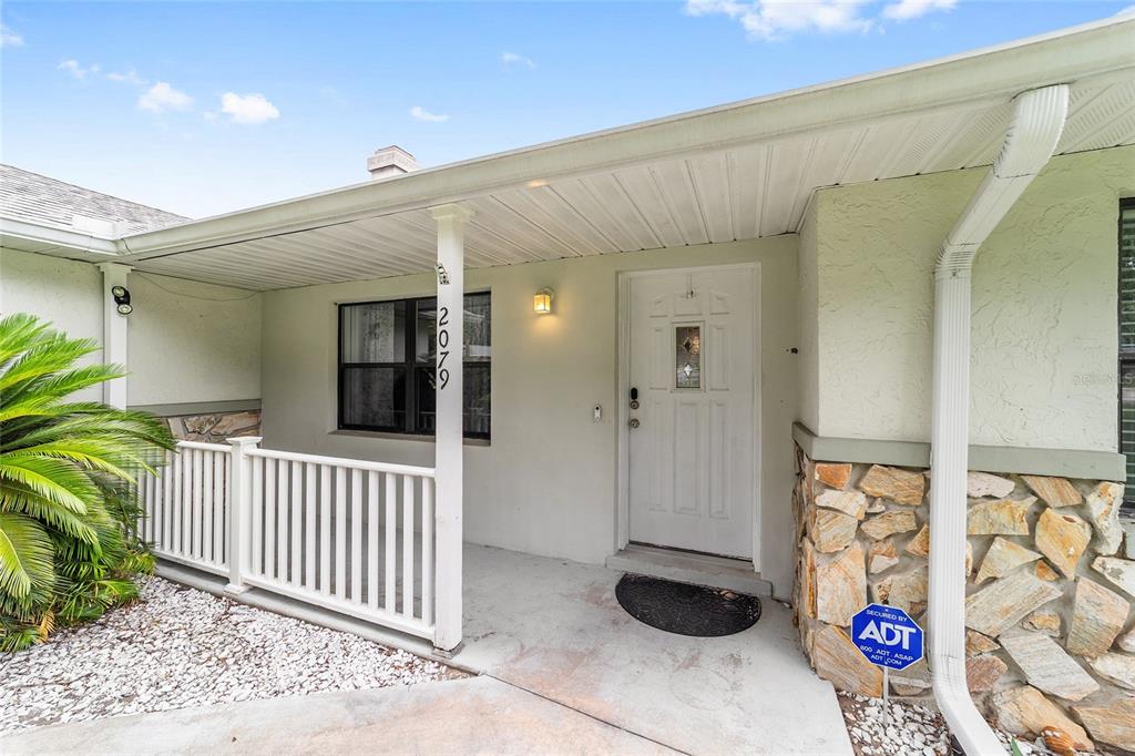 A covered front porch features a white railing, a white door, and stone siding — 2079 NE 43RD STREET, OCALA, FL