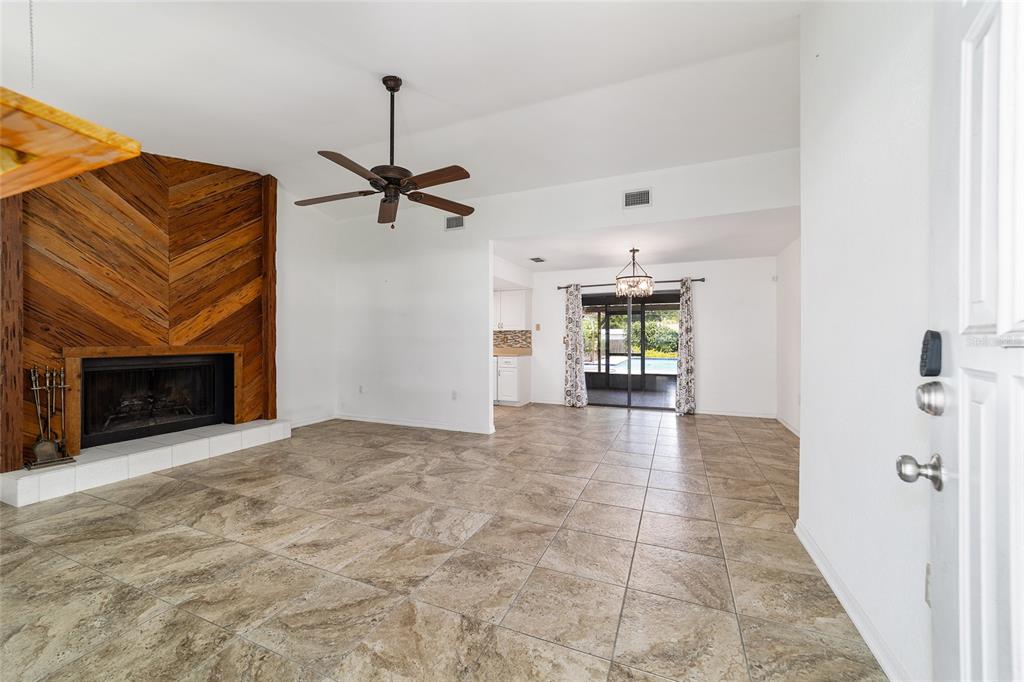 A living room features a wood-paneled fireplace, tile flooring, a ceiling fan, and sliding doors — 2079 NE 43RD STREET, OCALA, FL