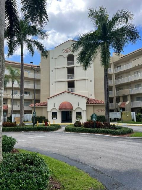 The exterior of a multi-story apartment building features a central entrance with a rounded roof — 10720 NW 66th St # 206, Doral FL 33178, DORAL, FL