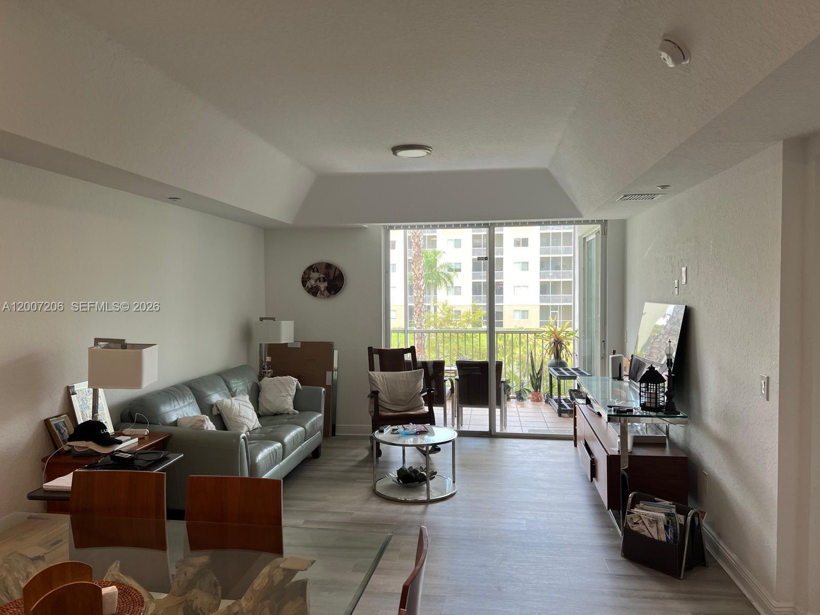 A living room features a light-colored sofa, glass coffee table, and sliding doors to a balcony — 10720 NW 66th St # 206, Doral FL 33178, DORAL, FL