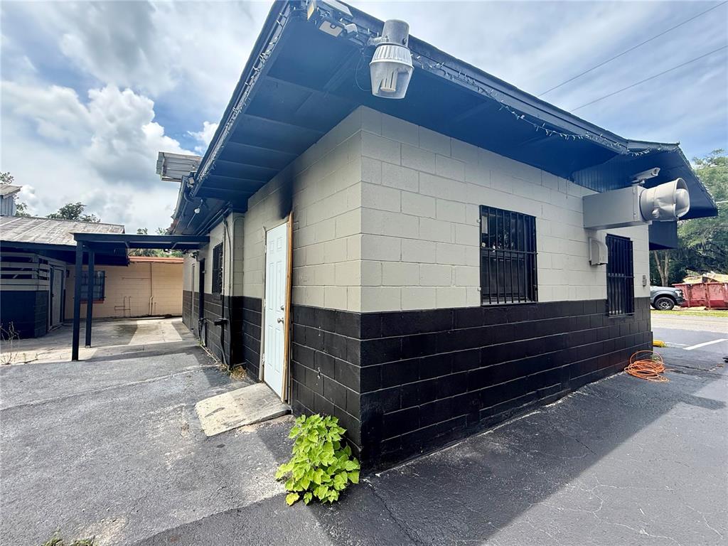 An exterior view of a concrete block building with a white door and barred windows — 503 PALMETTO STREET, EUSTIS, FL