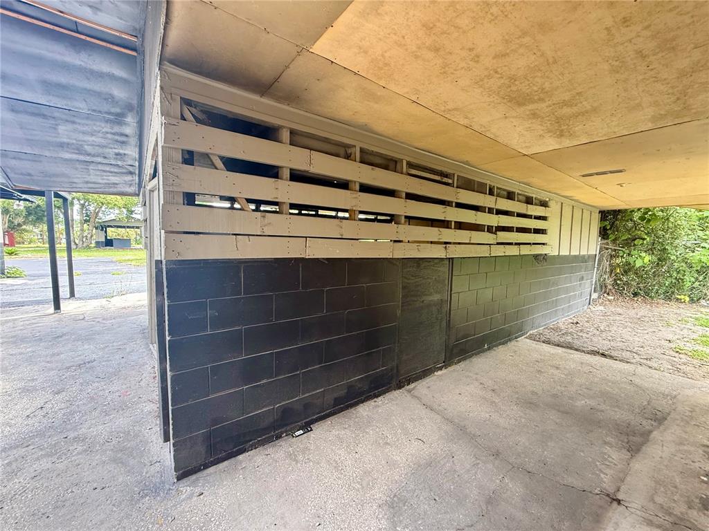 A concrete block wall with horizontal wood slats sits under a covered carport area — 503 PALMETTO STREET, EUSTIS, FL