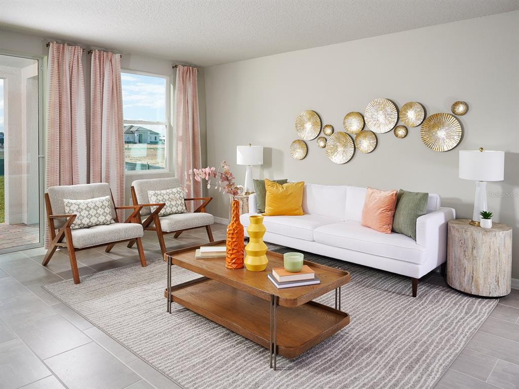 A living room features a white sofa, two armchairs, a wooden coffee table, and wall decor — 9126 DALERA COVE, PALMETTO, FL